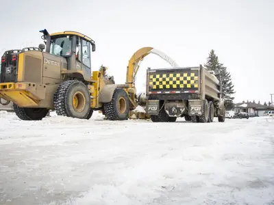 grader putting snow in dump truck